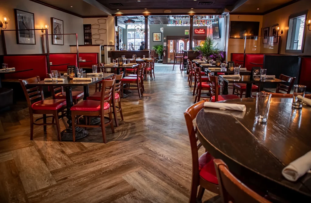 Warmly lit restaurant interior with red seating and acrylic dividers.