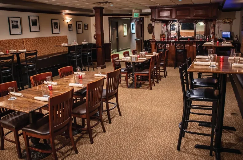 Classic restaurant interior with wooden tables, booths, and a dark wood bar.