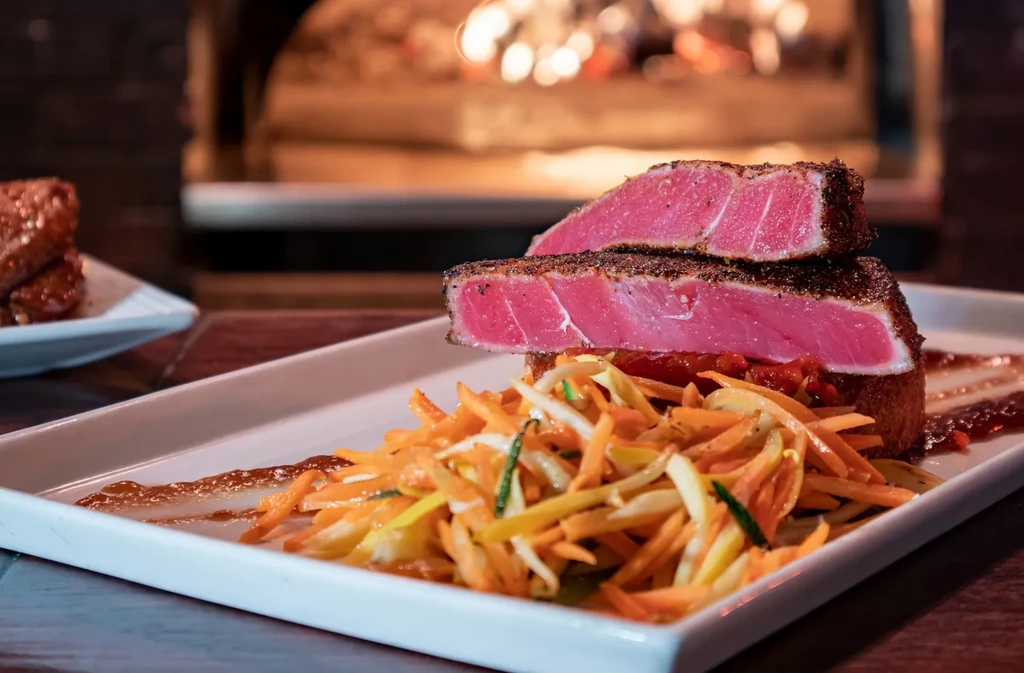 Seared rare ahi tuna, slaw, relish on plate, warm background.