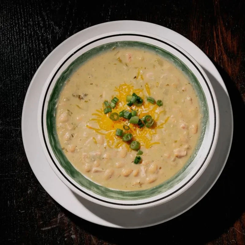 Overhead shot of creamy white bean chili garnished with cheese and scallions.