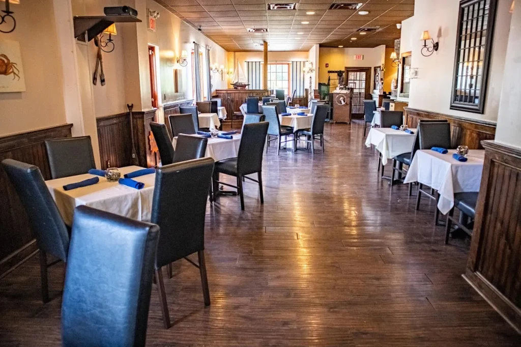 Long, empty restaurant dining room with set tables and warm lighting.