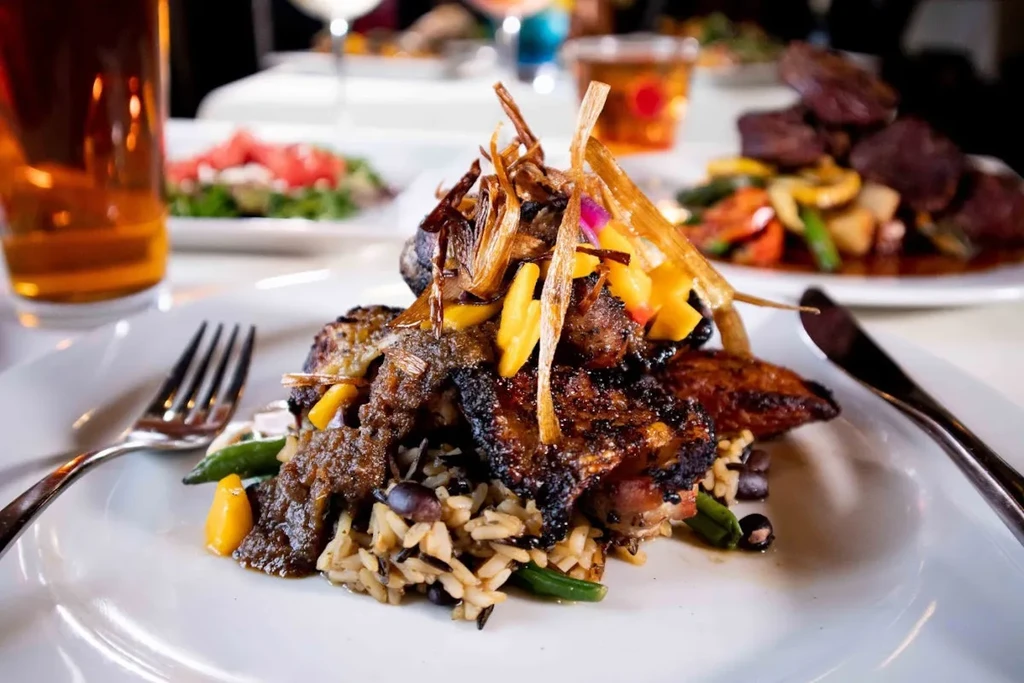 Grilled meat with rice and beans, garnished with crispy onions and sauce.