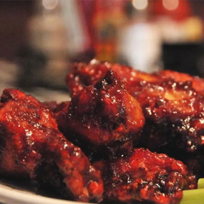 Piled glazed chicken wings with reddish-brown sauce and celery.