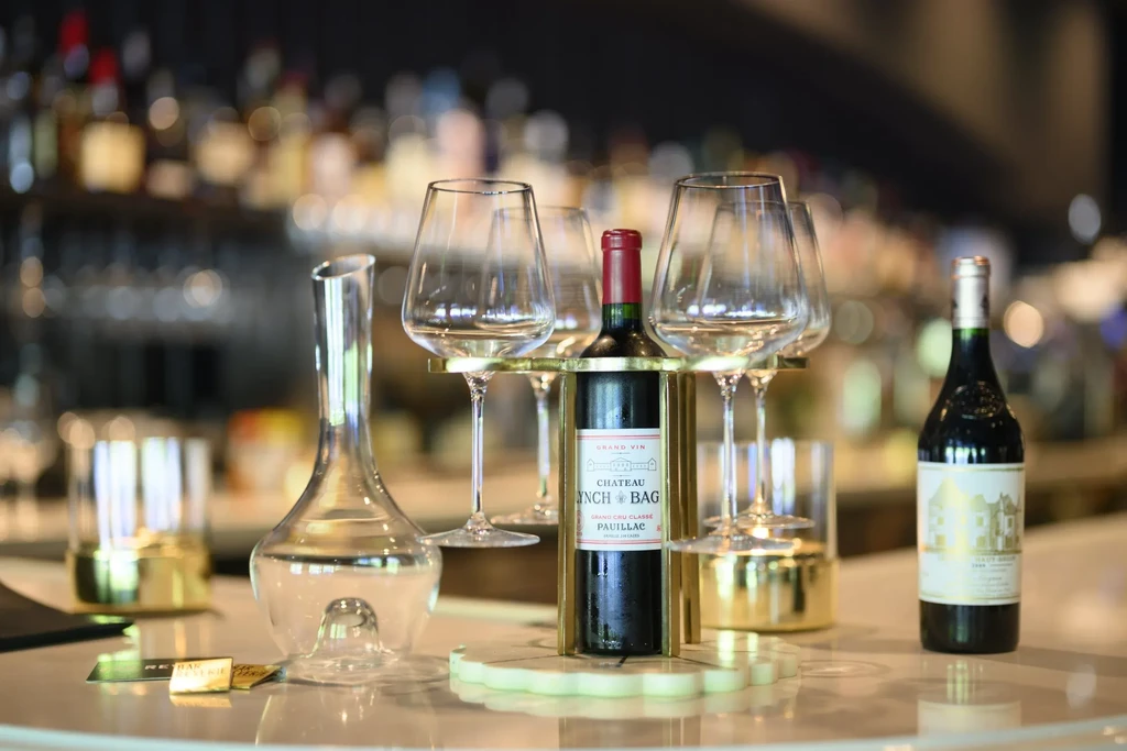Wine decanter, two red wines, and glasses on a sophisticated bar.
