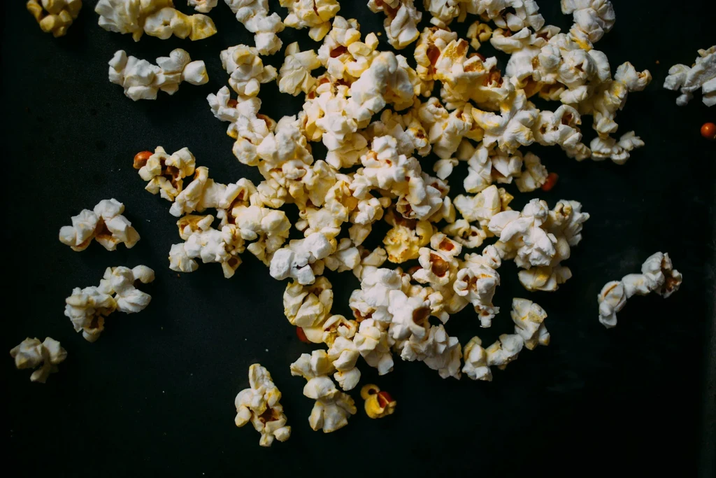 Top-down view of scattered buttery popcorn on a dark surface.