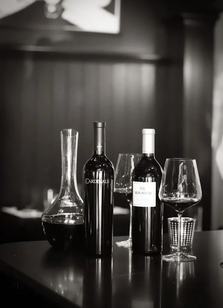 Black and white photo of wine bottles, decanter, and glasses.