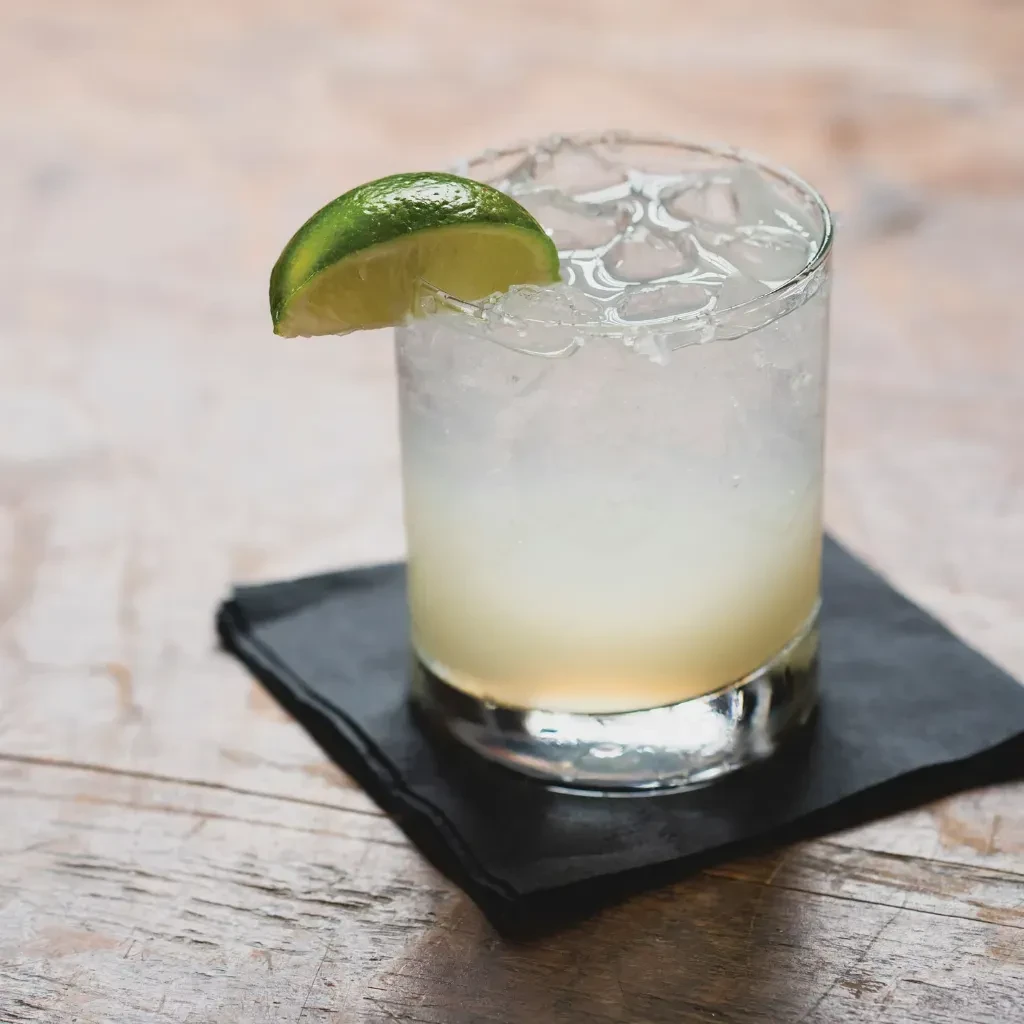 Cocktail with ice, lime wedge, and a salt-rimmed glass.