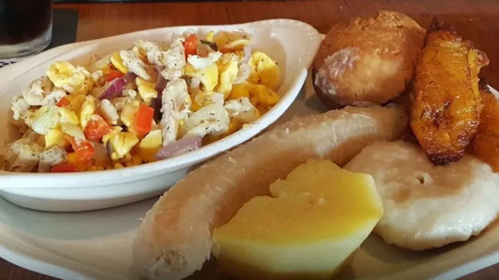 Plate of scrambled ackee and saltfish with plantain, yam, and dumplings.