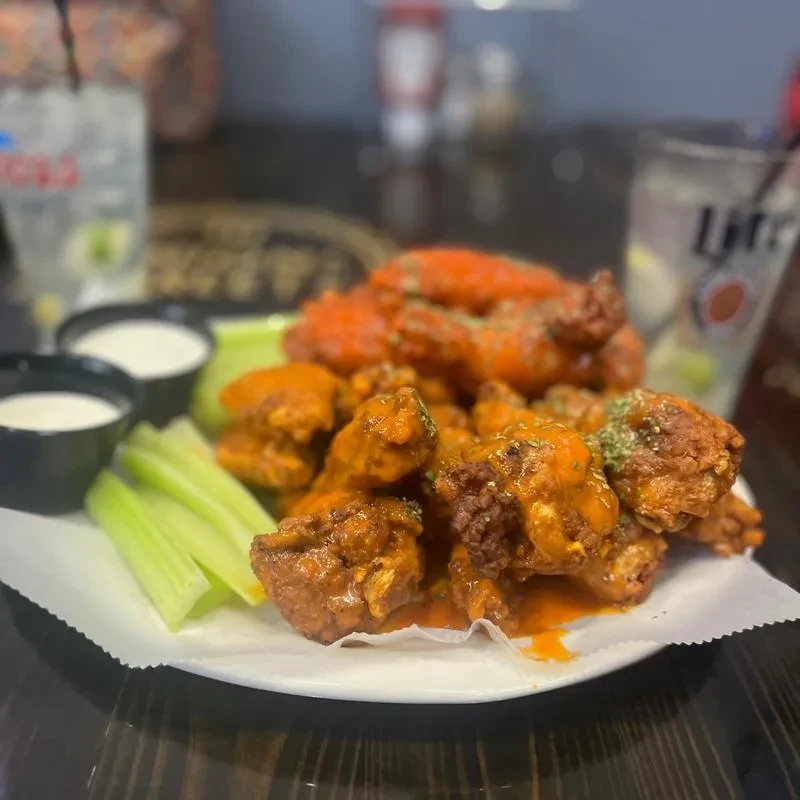 Large plate of buffalo wings, celery, dipping sauce, and two beers.