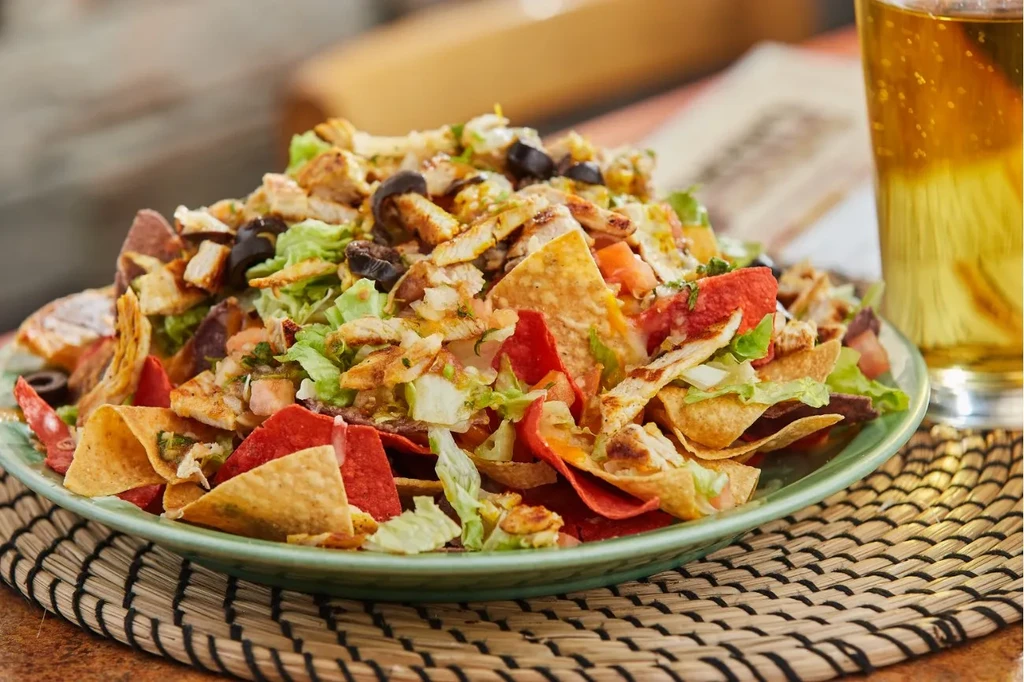 Generously portioned loaded nachos or taco salad with beer.