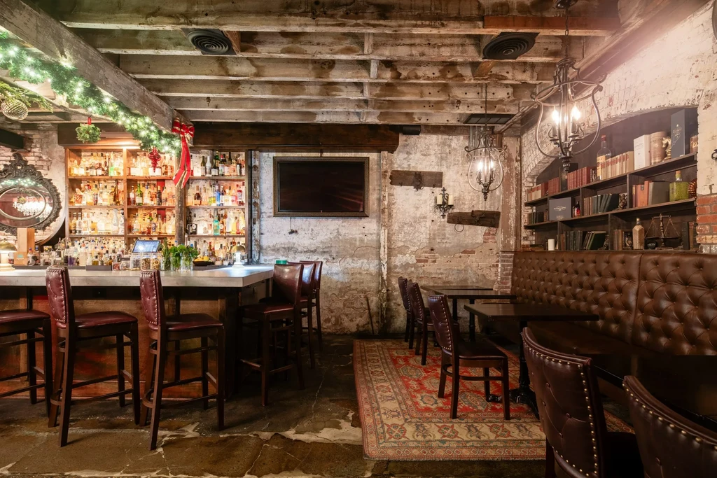 Dimly lit bar with festive garland, exposed brick, and leather seating.