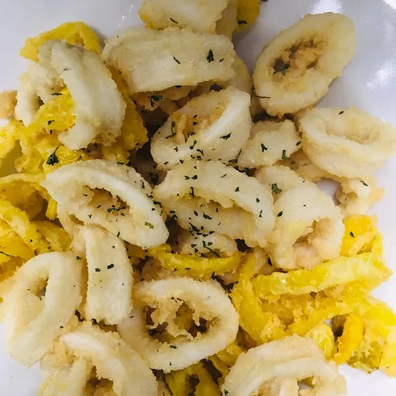 Fried calamari rings and yellow peppers garnished with green herbs.