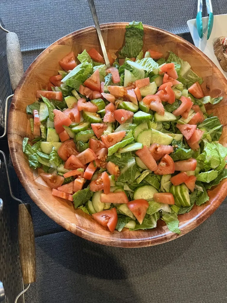 Fresh salad with lettuce, tomatoes, cucumbers in a wooden bowl.