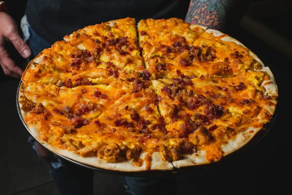 Sliced breakfast pizza with cheese, bacon, and scrambled eggs.