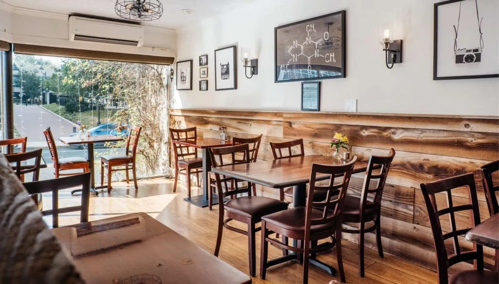 Empty cafe interior with wooden tables, rustic walls, and framed art.