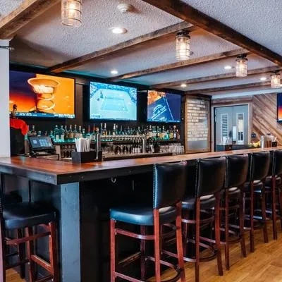 Modern bar counter, stocked with liquor, beer taps, and sports TVs.