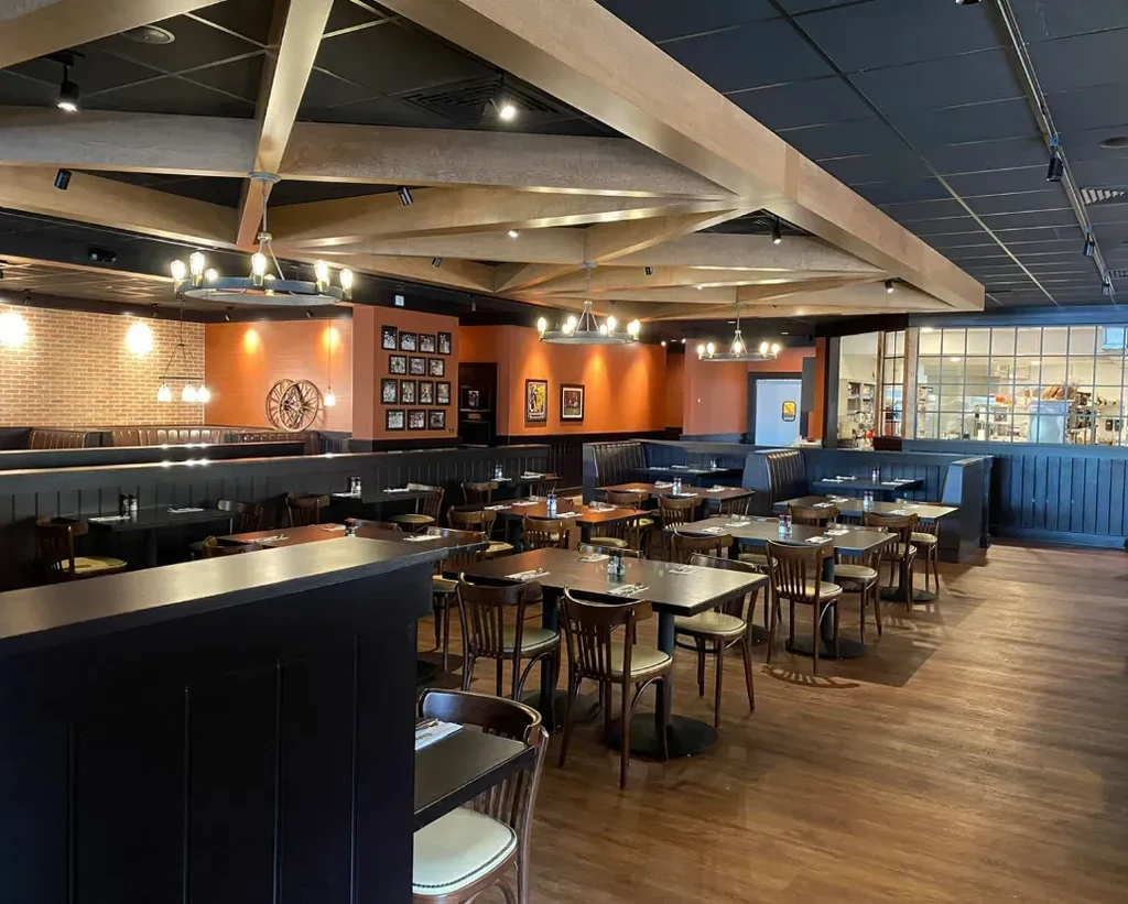 Empty restaurant dining area with warm lighting, wood, brick, and booths.