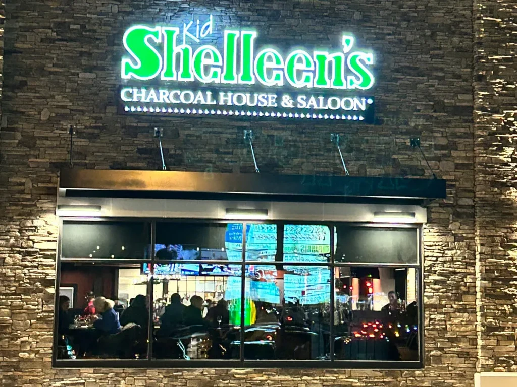 Kid Shelleen's restaurant exterior at night with a bright green neon sign.