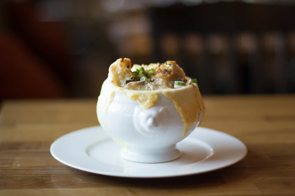 Close-up of French onion soup with melted cheese and chives.