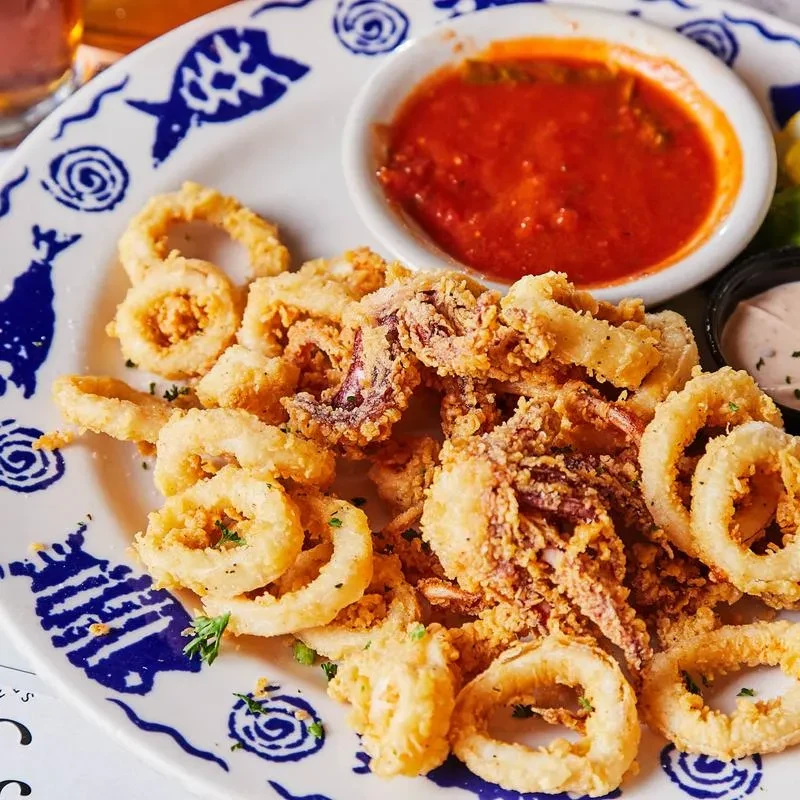 Crispy fried calamari with red and orange sauces on a nautical plate.