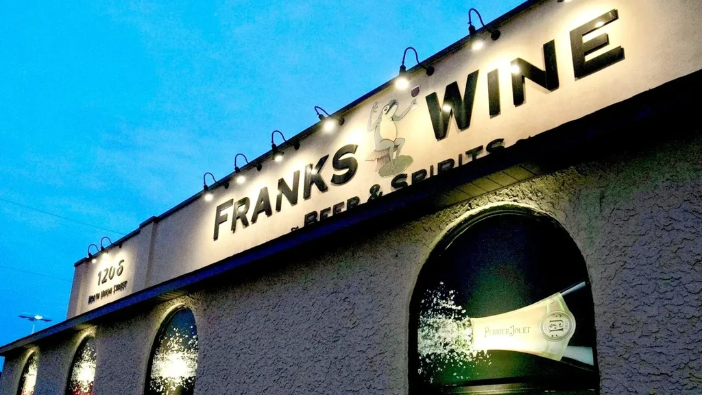 Illuminated 'Franks Wine Beer & Spirits' sign features a frog.
