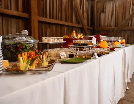 Long buffet table with autumn food, drinks, and rustic decor.