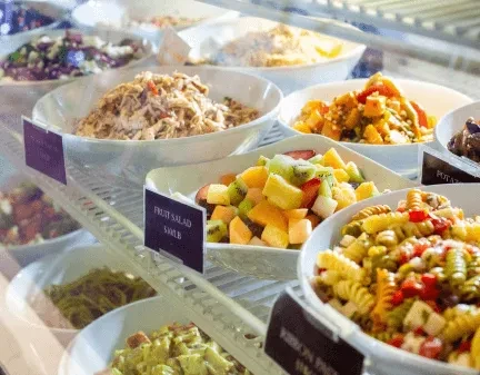Various salads and cold dishes in a refrigerated deli display case.