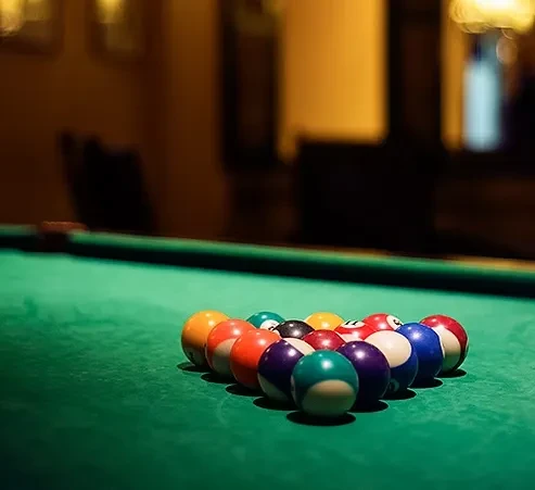 Close-up of colorful billiard balls racked on a green pool table.