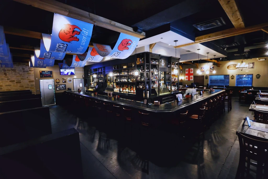 Dark, empty, rustic bar interior with U-shaped counter and elephant banners.