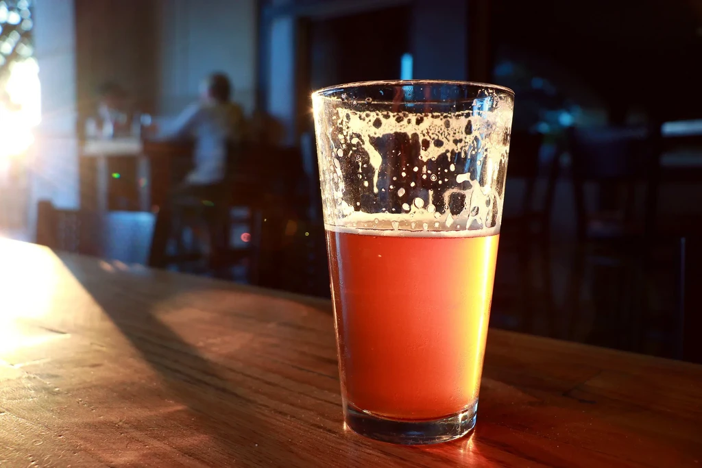 Amber beer in a glass on a wooden table, warm bar.