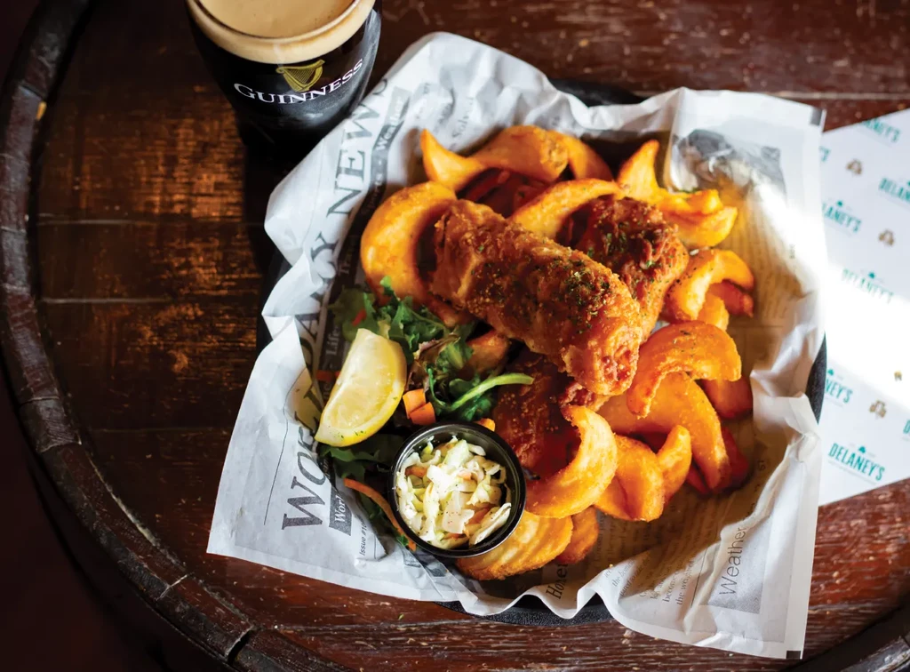 Overhead view of fish and chips with coleslaw, salad, and Guinness.