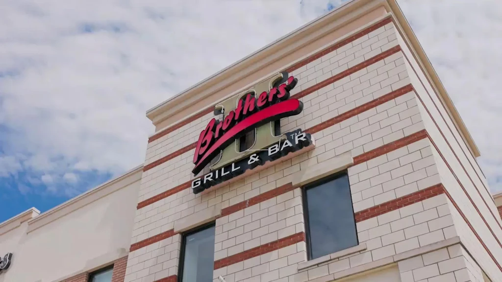 Upward view of Brothers II GRILL & BAR sign on light brick.