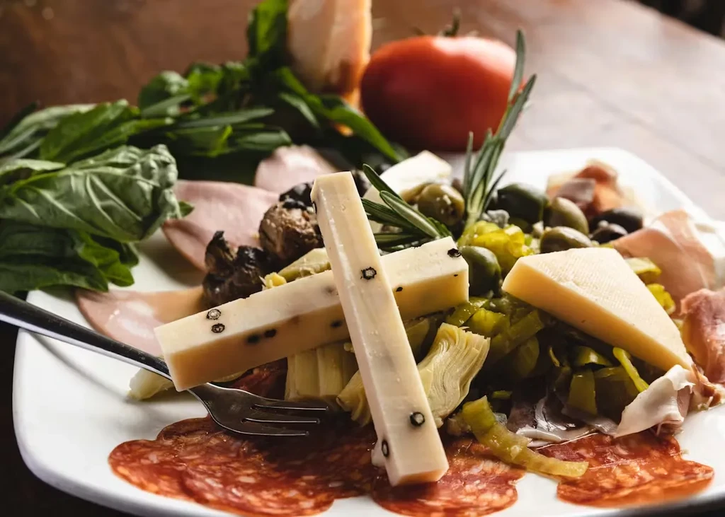 An antipasto platter with cheese, meats, olives, and artichoke hearts.