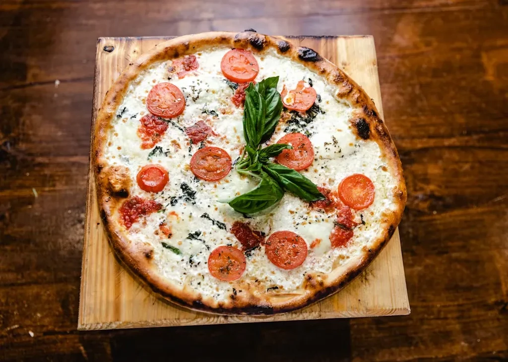 Freshly baked pizza with melted cheese, tomato, peppers, and fresh basil.