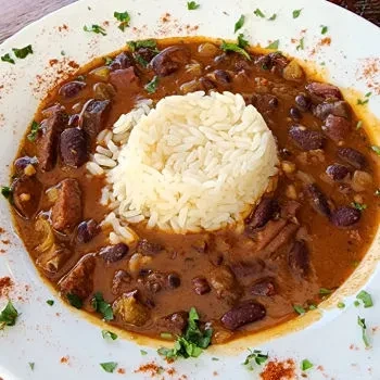 White rice encircled by meat and kidney bean chili, garnished with herbs.