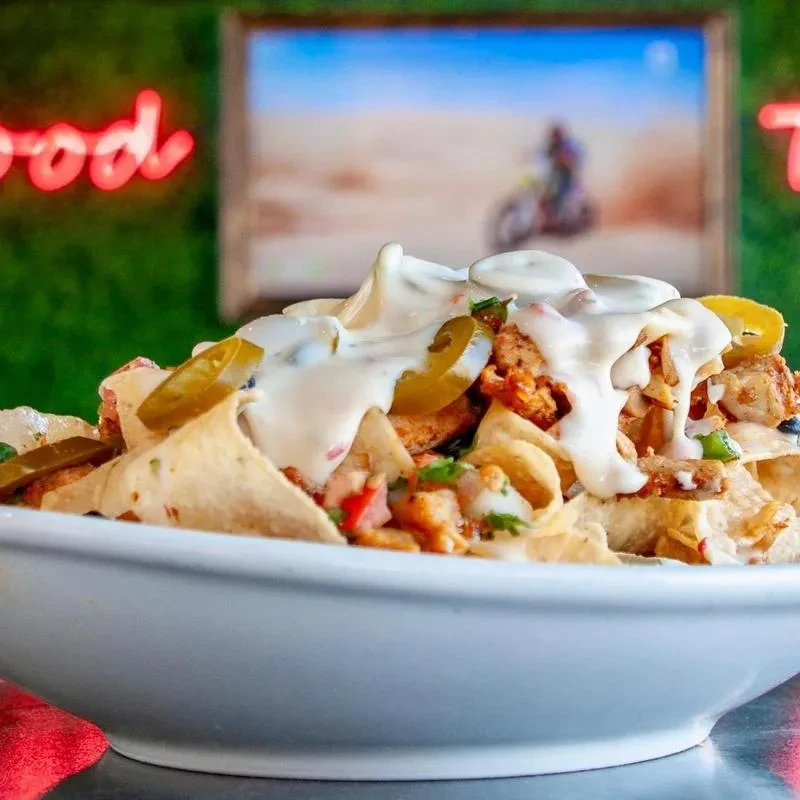 Close-up of loaded nachos with chicken, cheese, jalapeños, and pico de gallo.