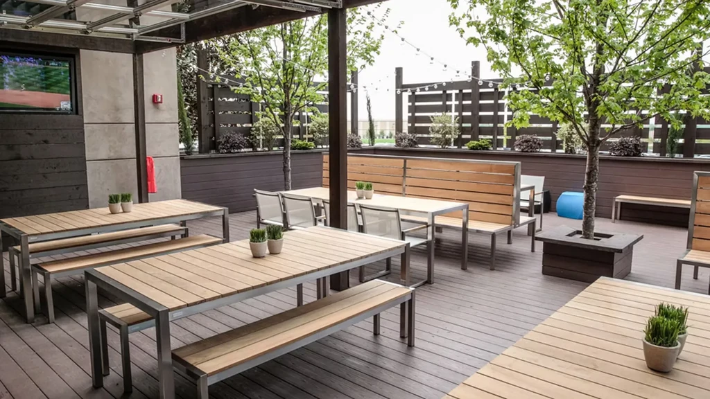 Expansive modern outdoor patio with wood furniture, string lights, and TV.