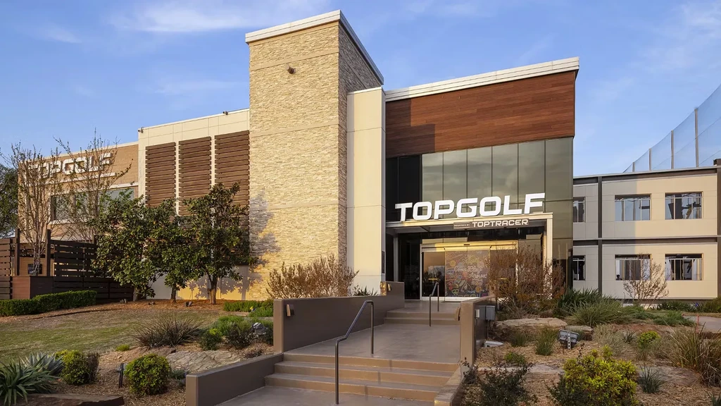 Topgolf building exterior with "Toptracer" sign and golf driving range netting.