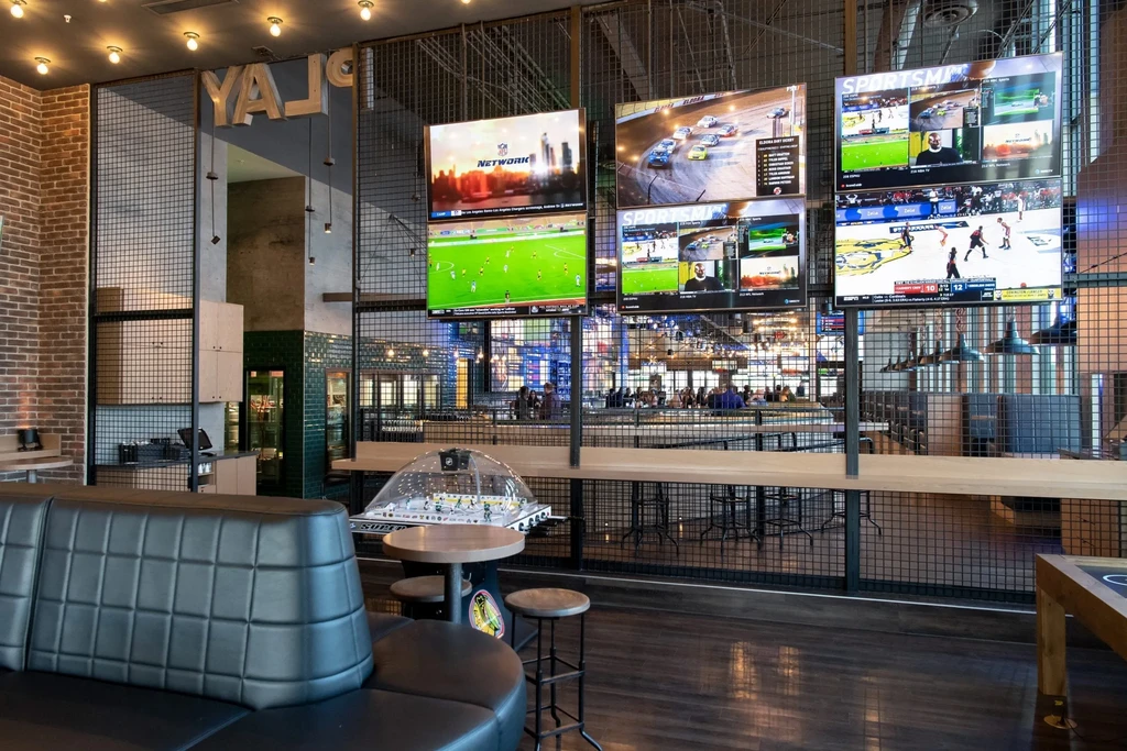 Bustling modern sports bar with multiple TVs and a hockey game.
