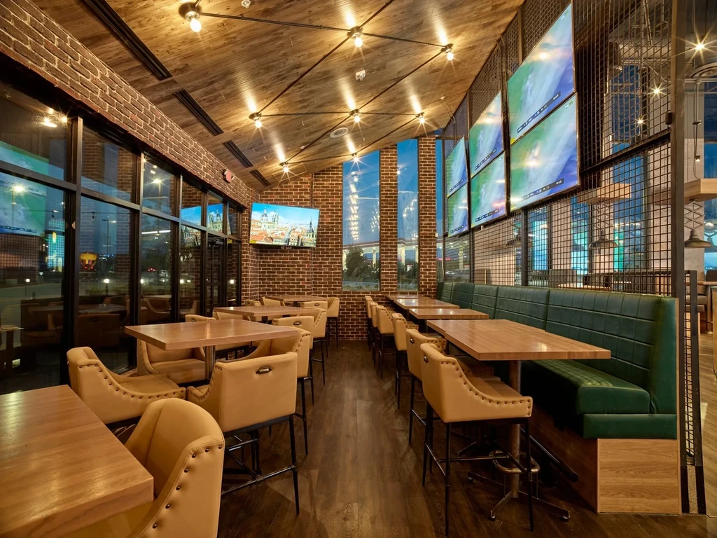 Empty modern sports bar interior with brick walls, booths, and large TVs.