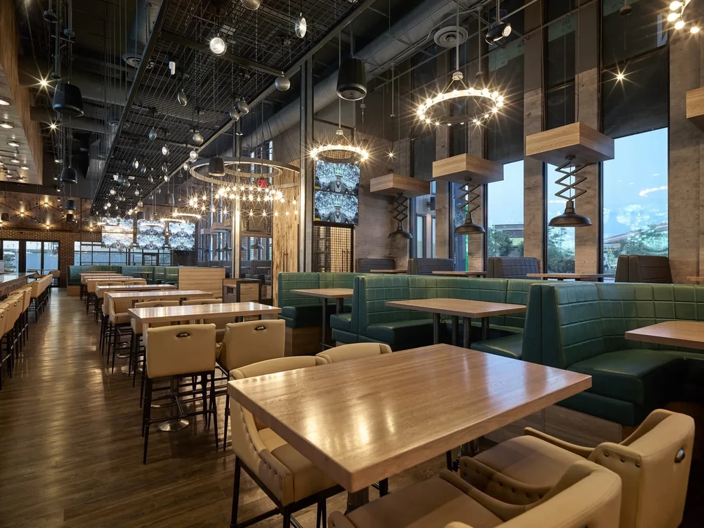 Empty modern restaurant interior with industrial ceiling, mixed seating, and large windows.