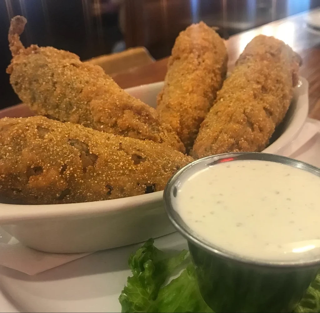Close-up of golden fried jalapeño poppers and creamy dipping sauce.
