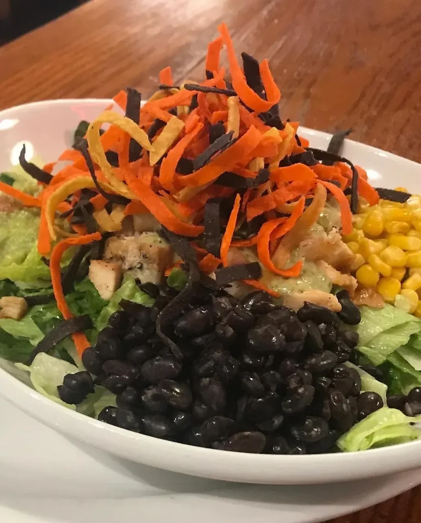 Southwestern salad in oval dish with chicken, beans, corn, and chips.