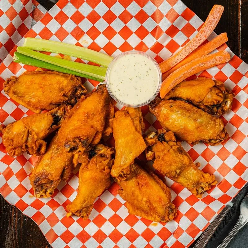 Crispy fried chicken wings with celery, carrots, and creamy dip.