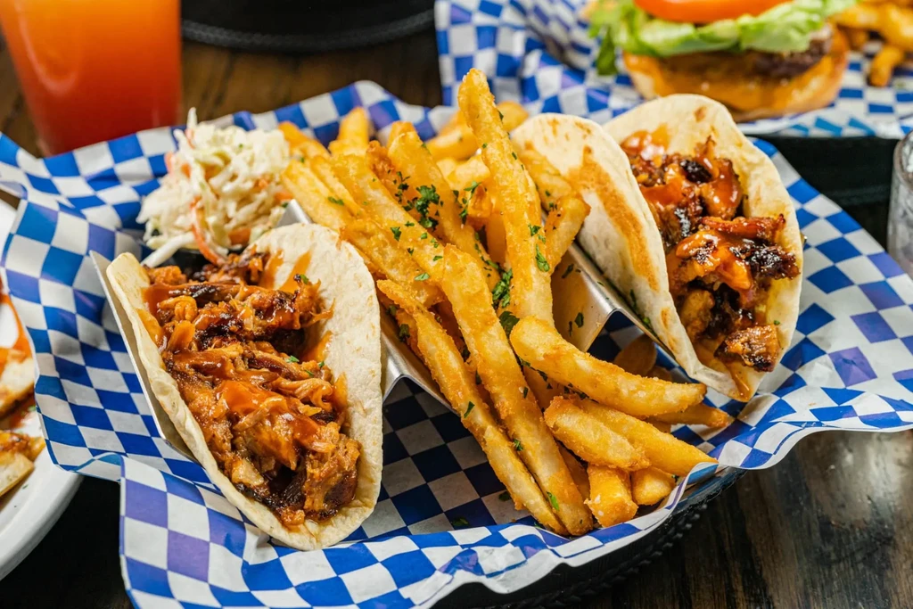 Basket of three pulled meat tacos with fries and coleslaw.