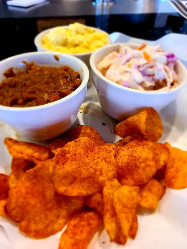 Platter with seasoned chips and three bowls of diverse side dishes.