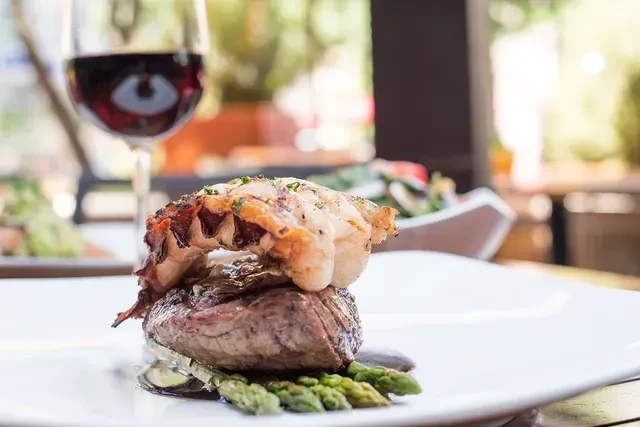 Steak topped with lobster tail, asparagus, and dark sauce.