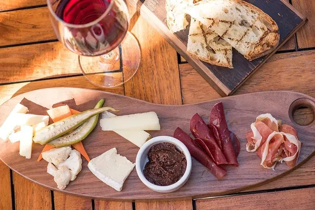 Overhead charcuterie and cheese board with red wine and grilled bread.
