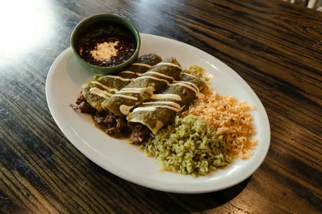 Mexican plate with green enchiladas, shredded meat, Spanish and green rice.