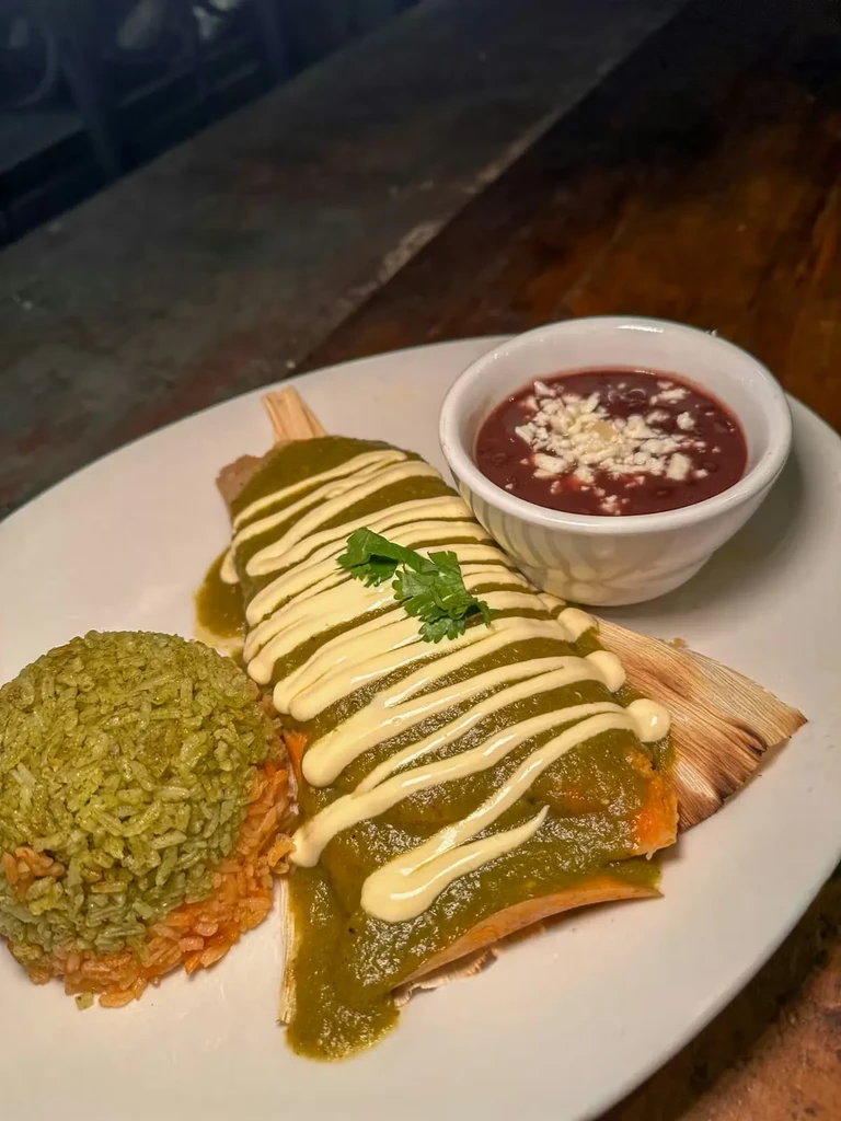 Vibrant tamale with green sauce, layered rice, and bean stew.